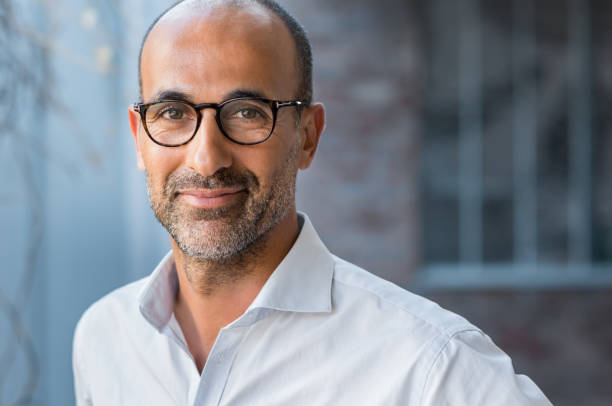 Mature mixed race man smiling Portrait of happy mature man wearing spectacles and looking at camera outdoor. Man with beard and glasses feeling confident. Close up face of hispanic business man smiling. eyewear photos stock pictures, royalty-free photos & images