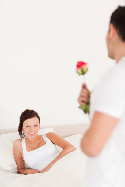 istock Young woman looking into camera when husband arrives with rose 825087614