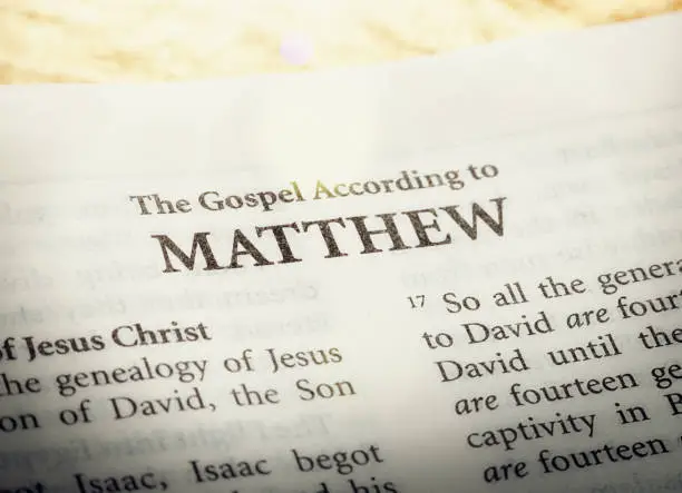 A copy of the Bible is open to the title page of ther first book of the New Testament, the Gospel according to Matthew.