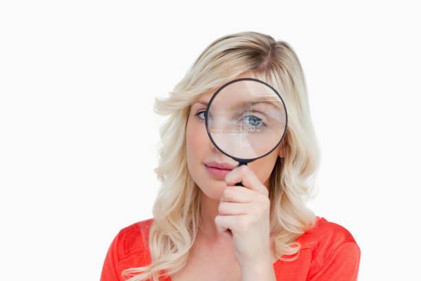 istock Fairhaired woman looking through a magnifying glass 825113228