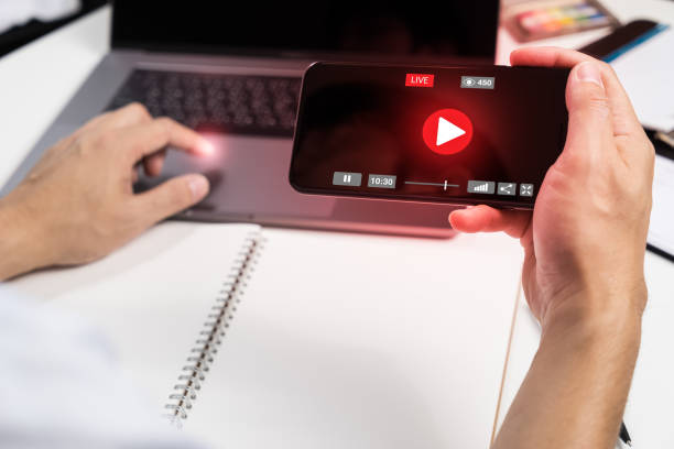 istock Man Hand HoldingSmart phone with Live Streaming with Modern laptop computer .Internet social  marketing concept 825113758