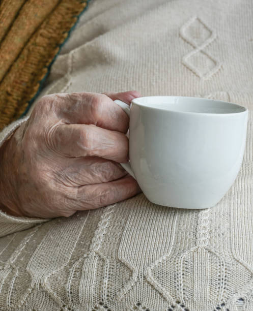 istock wrinkled hand holding a cup of tea 825116562