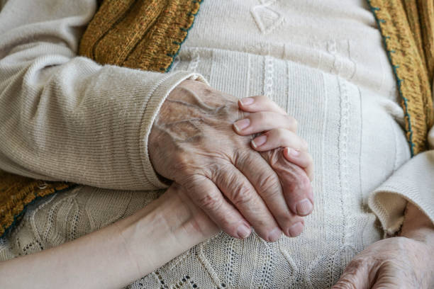 istock wrinkled hand holding a younger hand 825116582
