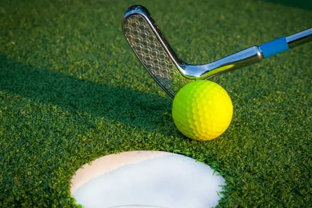 Photo of Close up image of golf hole with yellow ball and putt