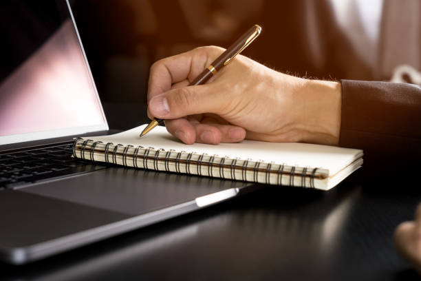 istock Asian hand writing his idea on notebook paper and modern laptop computer 825121416