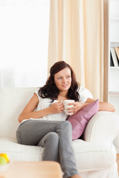 istock Young Woman holding a cup looking out the window 825124684