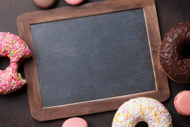 istock Chalkboard and colorful donuts on stone table 825126846
