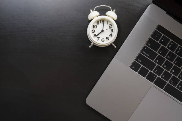 istock Modern laptop with white clock on wooden table .work and time concept 825145986