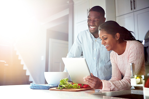 Shot of a young couple using a digital tablet while preparing a healthy meal together at home