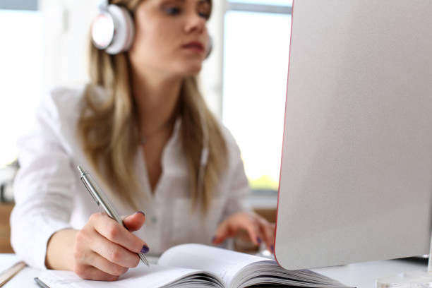 istock Beautiful woman wearing headphones making notes 825155342
