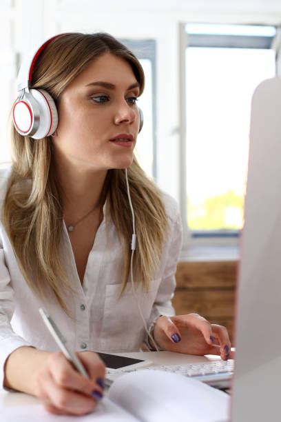 istock Beautiful woman wearing headphones making notes 825155358