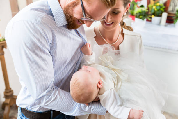 Parents with baby at christening in church Young parents at the church with their baby wearing a christening gown baptism photos stock pictures, royalty-free photos & images