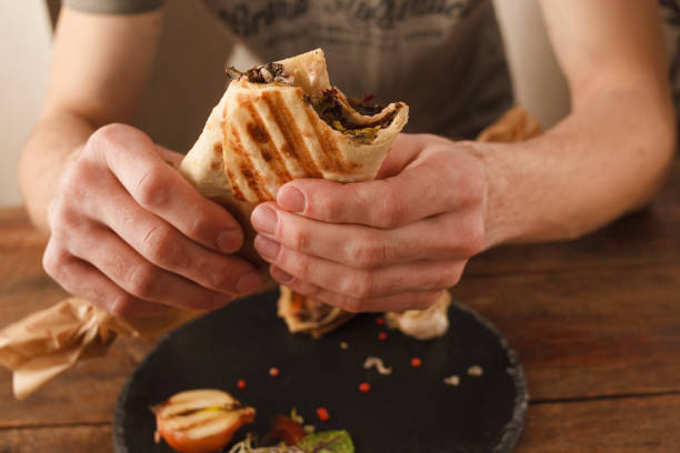 istock Man eating shawarma close up 825160444