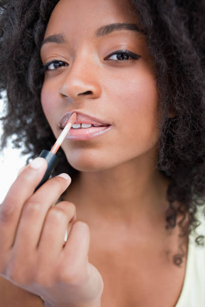 istock Young woman applying gloss in a concentrated way 825160790
