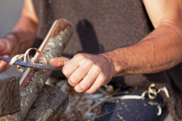 Bazoges-en-Pareds, France - July 29 2017: A medieval carpenter planing a branch of wood during the annual \