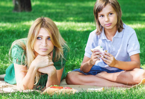 istock Family breakfast on grass. Mom and son eating sandwich 825171130