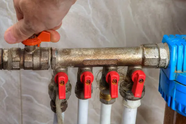 Photo of Human hand turn off shut-off valve home water supply.