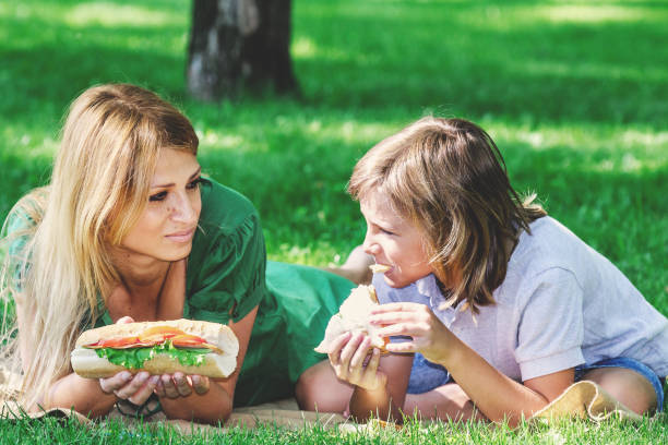 istock Family breakfast on grass. Mom and son eating sandwich 825171382