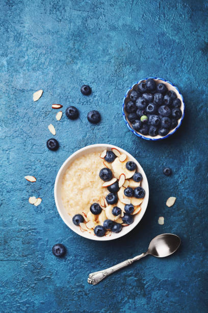 mingau de aveia com banana e mirtilo na vista de topo de mesa vintage em estilo apartamento leigo. comida quente, café da manhã e dieta. - oatmeal heat bowl breakfast - fotografias e filmes do acervo