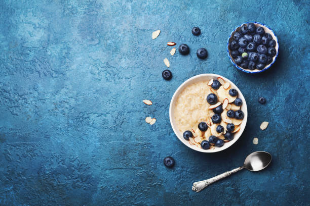 Bowl of oatmeal porridge with banana and blueberry on vintage table top view in flat lay style. Healthy breakfast. Bowl of oatmeal porridge with banana and blueberry on vintage table top view in flat lay style. Healthy breakfast and diet food. oats food stock pictures, royalty-free photos & images
