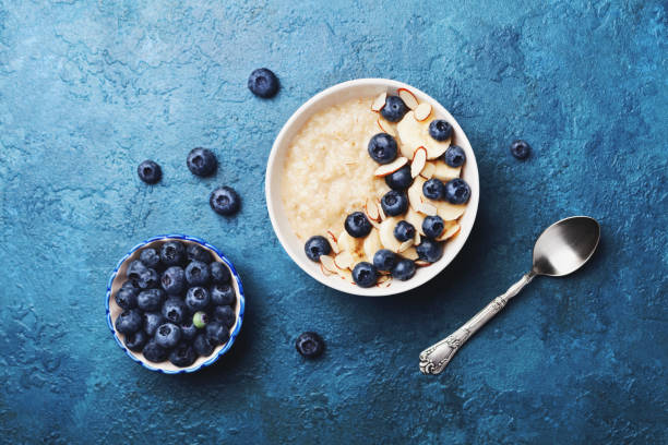 tigela de mingau de aveia com banana e mirtilo na vista de topo de mesa vintage em estilo apartamento leigo. pequeno-almoço caseiro. - oatmeal heat bowl breakfast - fotografias e filmes do acervo