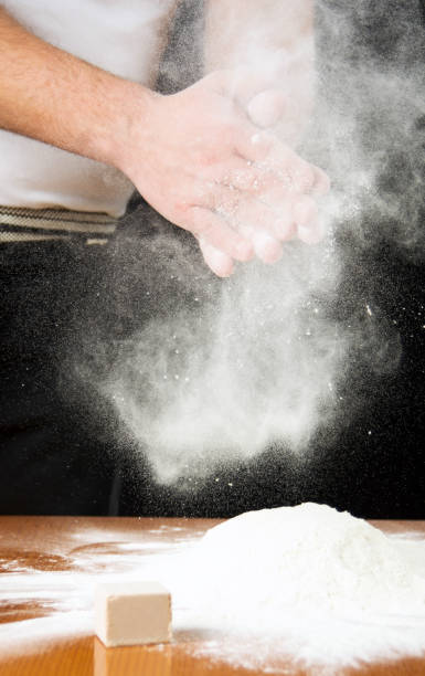 istock Male baker shaking out flour from his hands 825180974