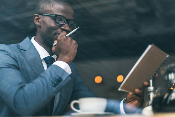 istock thoughtful handsome african american businessman with coffee cup working in cafe 825187012