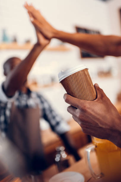 istock african american barista giving highfive to client with disposable cup in coffee shop 825187708