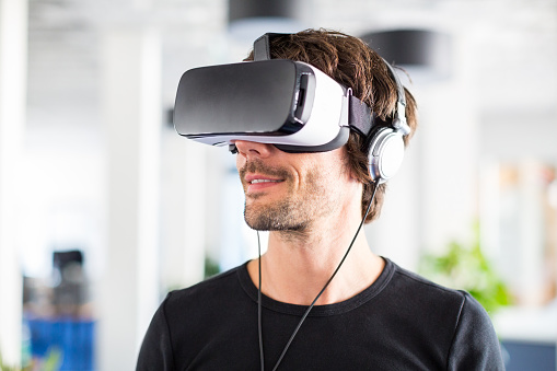 Closeup shot of young man using virtual reality glasses in office. Entrepreneur testing virtual reality simulator headset.