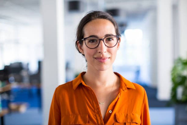 Young businesswoman with eyeglasses in office Portrait of a young businesswoman with eyeglasses standing in office. Female entrepreneur looking at camera. taking a break photos stock pictures, royalty-free photos & images