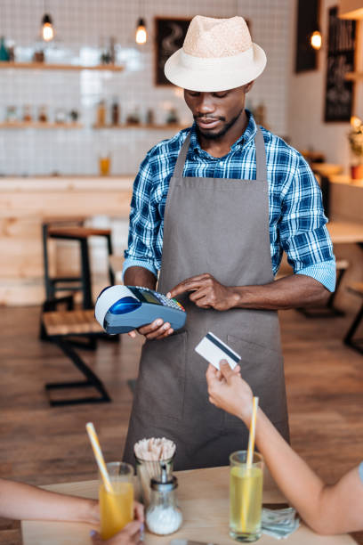 istock handsome african american waiter using terminal for doing credit card payment in cafe 825191672