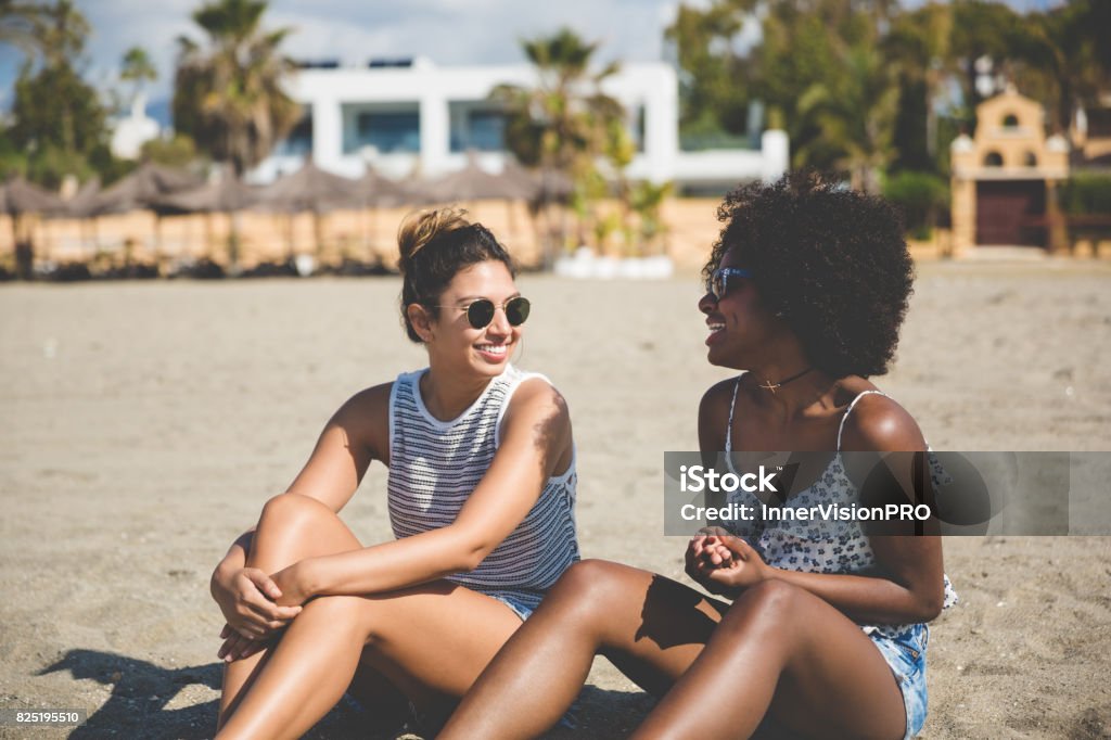 Dwie ładne dziewczyny siedzące na plaży rozmawiają - Zbiór zdjęć royalty-free (20-29 lat) Dwie ładne dziewczyny siedzące na plaży rozmawiają - Zbiór zdjęć royalty-free (20-29 lat)