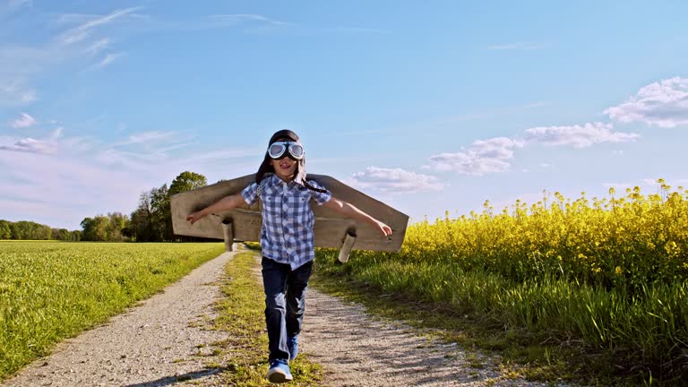 SLO MO Little boy running on a dirt road in an airplane costume