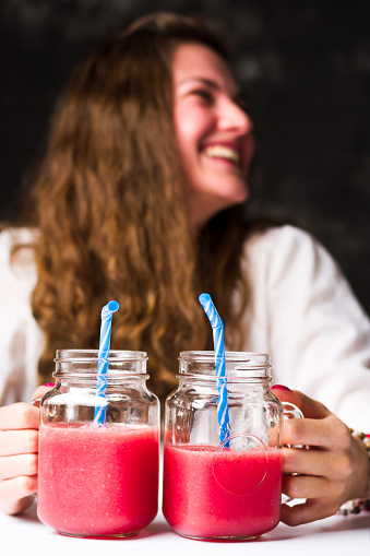 Female holding fresh watermelon smoothies in jars