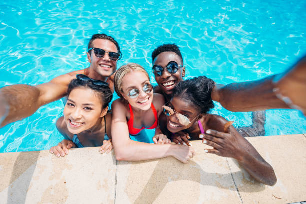 Group of young happy multiethnic people taking selfie in swimming pool Group of young happy multiethnic people taking selfie in swimming pool the black womens expo stock pictures, royalty-free photos & images