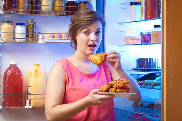 молодая женщина нездоровое питание перед холодильником - deep fried people fried chicken стоковые фото и изображения