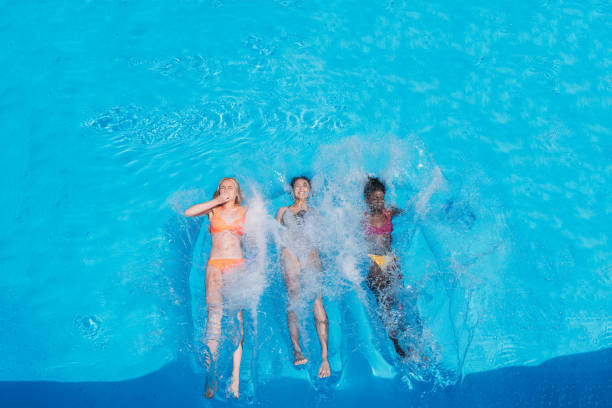 istock Three happy multiethnic women swimming on backs in pool at resort 825203878