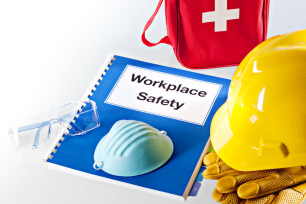 Workplace Safety Manual Document Book  with Safety Equipment Still Life A still life of a Workplace Safety Manual instruction book, with a variety of safety equipment such as hard hat, work gloves, eye gargles breathing dust mask and first aid pack. helmet hardhat protective glove safety stock pictures, royalty-free photos & images