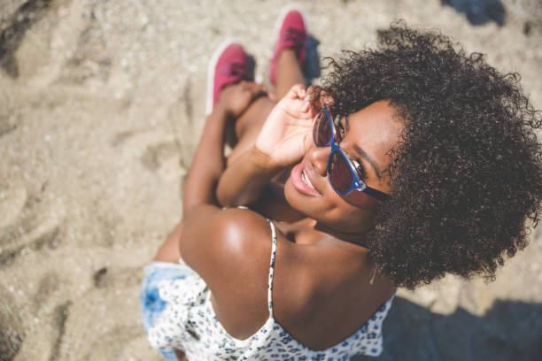 istock Young afro american girl sitting on sand smiling 825204566