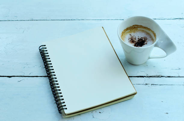 istock Cup of cappuccino and notebooks on wooden table backgrounds 825208438