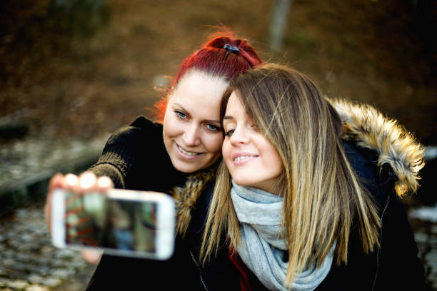 istock Image of cheerful young two women outdoors in park make selfie 825208618