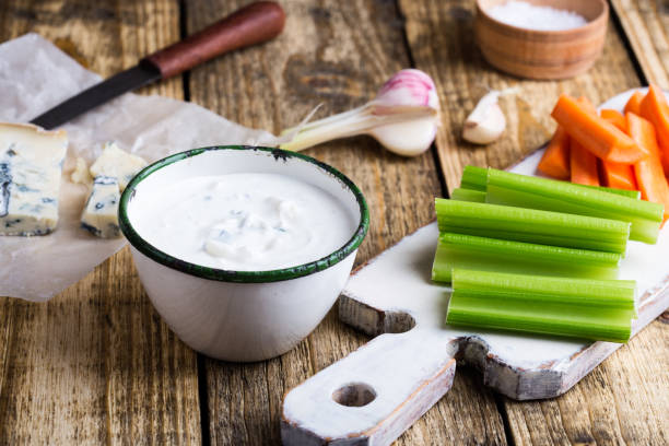 Mug of fresh blue cheese garlic dip sauce with celery and carrot sticks Mug of fresh blue cheese garlic dip sauce with celery and carrot sticks on wooden rustic table blue cheese stock pictures, royalty-free photos & images