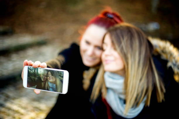 istock Image of cheerful young two women outdoors in park make selfie 825212030