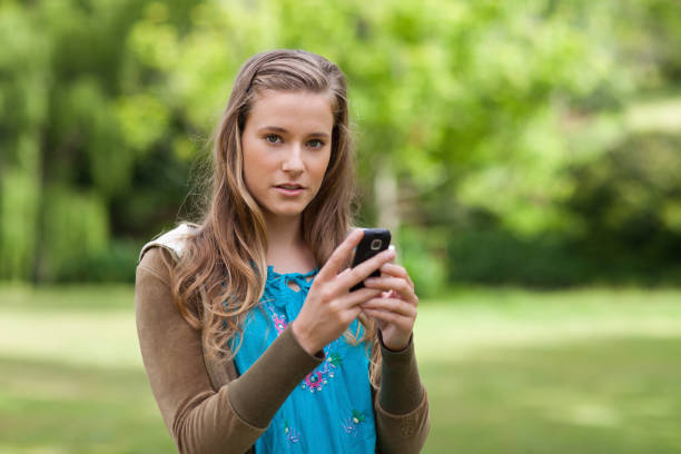 istock Teenage girl sending a text while looking at the camera 825219820