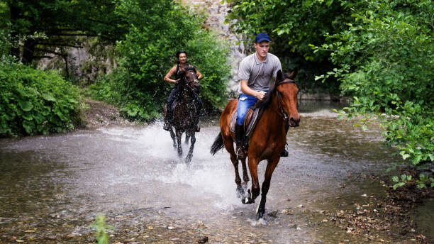 istock Friends riding his horse on the river 825222496