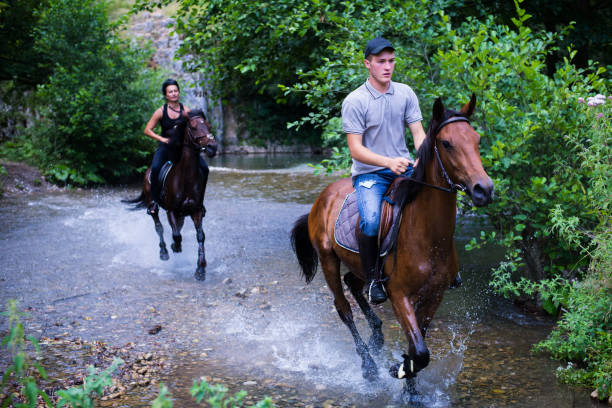 istock Friends riding his horse on the river 825226654