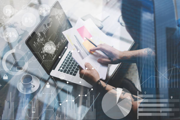 istock Concept of digital screen,virtual connection icon,diagram,graph interfaces.Adult tattooed coworker working with laptop at workplace.Businessman analyze documents on hands.Double exposure background. 825226758