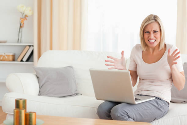 istock Angry blonde woman using a laptop 825237782