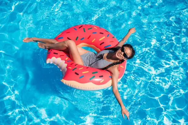 Photo of Young asian woman floating on inflatable donut in swimming pool