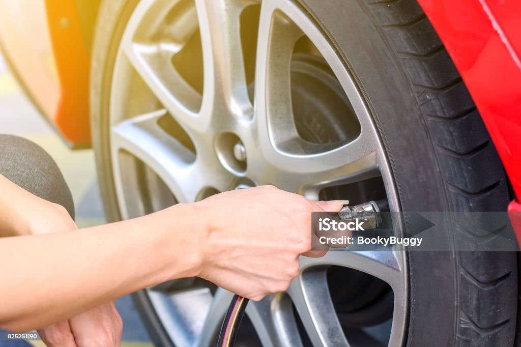 Woman Filling air into a car tire to increase pressure Tire - Vehicle Part Stock Photo